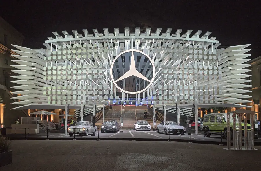 Mercedes-Benz brand presence at IAA Mobility 2025 in Munich at night: illuminated facade with a large star and cars in front