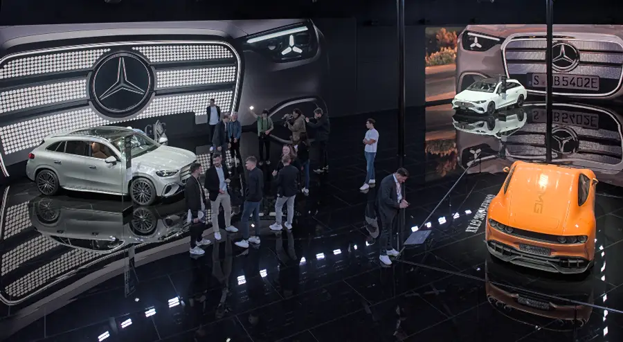 Mercedes-Benz exhibition stand at IAA Mobility 2025: cars on a reflective floor in front of large Mercedes stars, with visitors