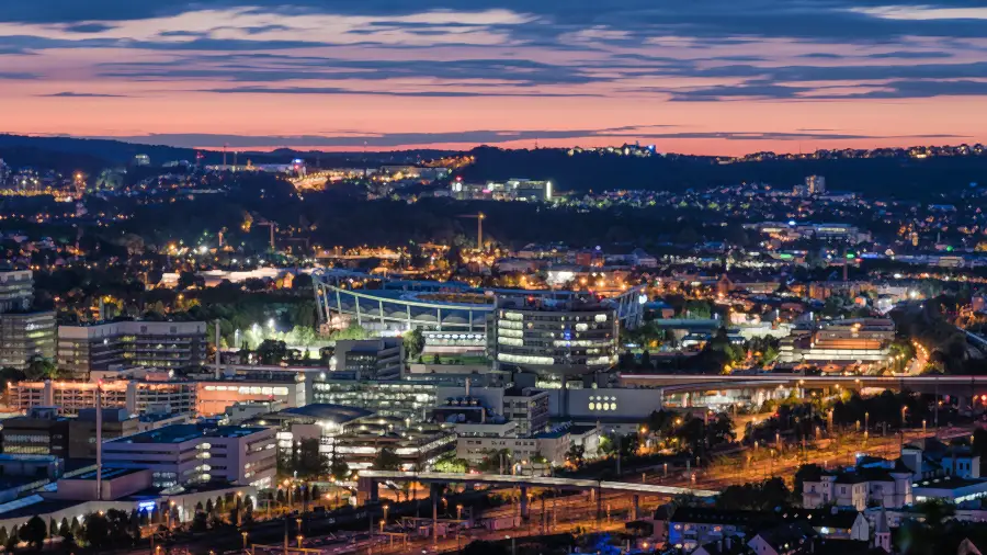 The Mercedes-Benz Untertürkheim plant by the Neckarpark in Stuttgart at dusk, with the city lights behind it